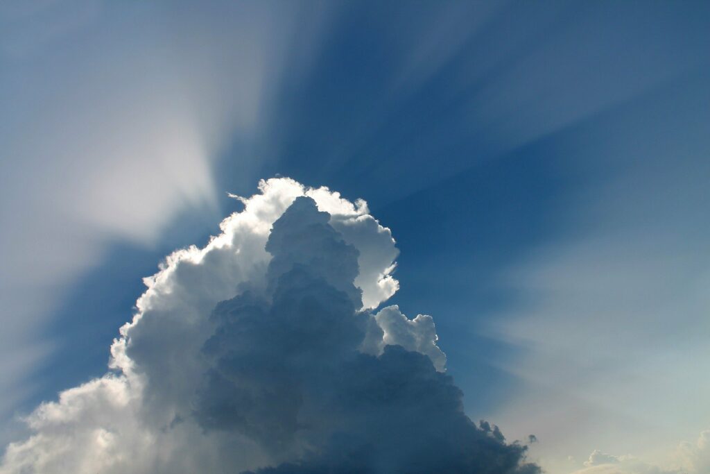 Hinter einer großen Wolke scheinen Sonnenstrahlen hervor. Online-Therapie löst Blockaden.